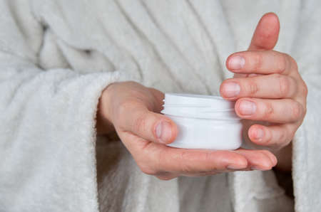 Woman hands with hand cream. Get cream from container.