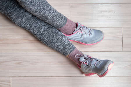Fit female leg in sport shoe sit on floorの写真素材