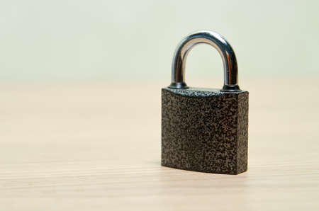 A metal padlock stands on a wooden tableの写真素材