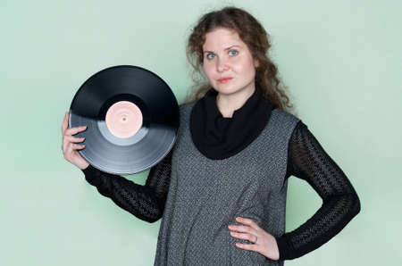 Smiling woman with curly hair listening to music with headphones and dancing