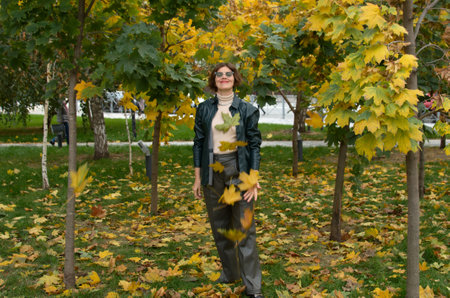 A woman in leather clothes stands against the backdrop of an autumn maple square