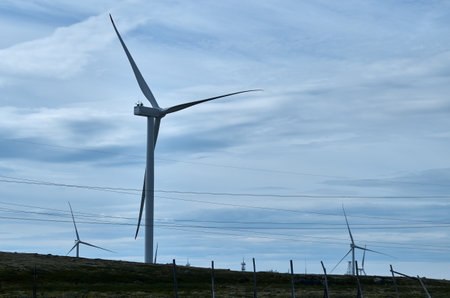 Wind farm in hilly area under cloudy sky