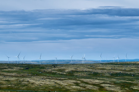 Wind farm in hilly area under cloudy sky