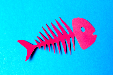 Red april fool fish cut out of colored paper on a cyan backgroundの写真素材
