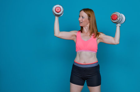 Woman doing physical exercises with very heavy dumbbellsの写真素材
