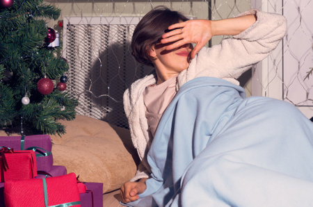 A woman in home clothes wakes up on Christmas morning under a mowed Christmas tree next to giftsの写真素材