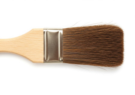 A close-up studio shot of a paint brush with a wooden handle and brown bristles, isolated on a white background. The metal ferrule connects the handle to the bristles, creating a tool for artistic expression.の素材