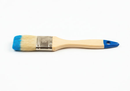 A paint brush with a wooden handle and blue paint on the bristles and handle tip. It is isolated on a white background. The brush is new and clean, ready for painting projects.の素材