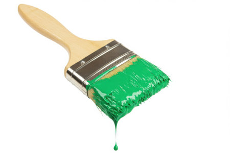 A paintbrush with a wooden handle and green paint on the bristles. A drop of green paint is falling from the brush. The background is white, creating a clean and bright image. Perfect for renovation or art concepts.の素材
