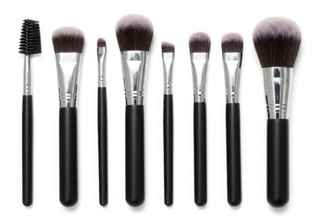 A set of makeup brushes with black handles and silver ferrules. The brushes have different shapes and sizes for various makeup applications. Arranged against a white backdrop, they are clean and ready for use.の素材