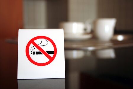 A white no smoking sign displayed on a table in a cafeの写真素材