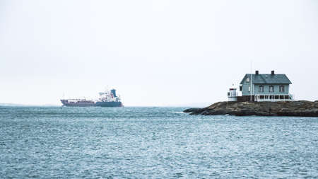 Tiny blue lighthouse on swedish coastline with big boat on background