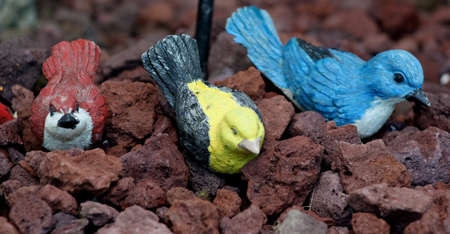 Bird statues resting in garden rocksの写真素材
