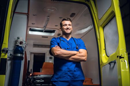 Doctor stands and smiles in the ambulance car
