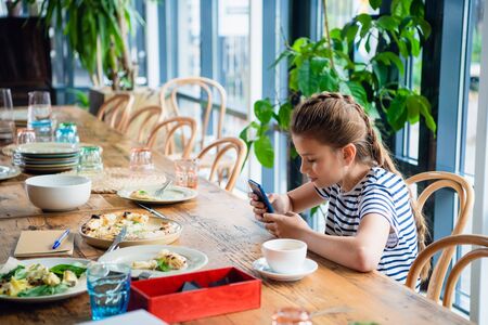 A pretty girl playing on her smartphone in the kitchenの写真素材