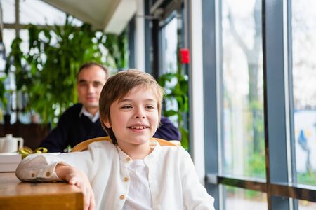 A boy on a family dinner smiling at someone he sawの写真素材