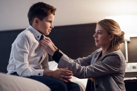 A Mother helping her son to take off his school uniform, while hの写真素材