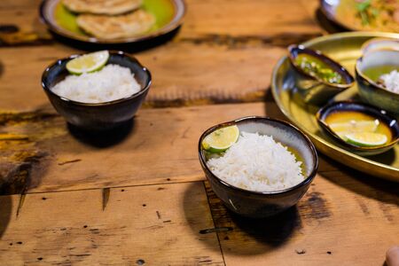 Small ceramic bowls with jasmine rice on a barked wooden tableの写真素材