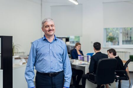A portrait of a smiling senior office manager with his team on tの写真素材