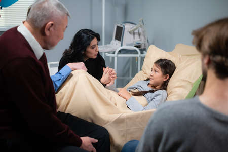 Relatives visiting a little girl in a hospital, she is recovering