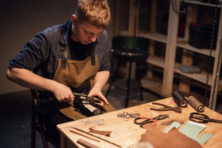 a young apprentice makes blanks for the production of shoes in the workshop.の写真素材