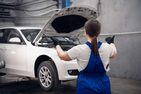 Female repairer lifts a car using a lift in a garageの写真素材
