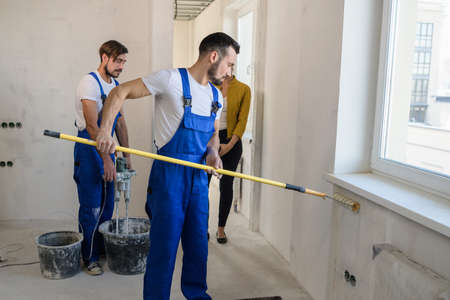 Builders are doing repairs. They use a roller and mixer