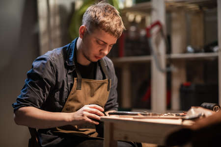 a young apprentice makes blanks for the production of shoes in the workshopの写真素材