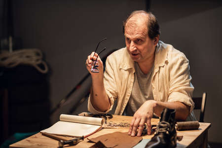 an old shoemaker makes shoes out of leather and answers questions from his apprentices in the...