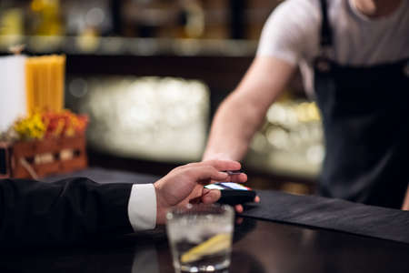 the man pays the bartender for the order with a credit card.の写真素材