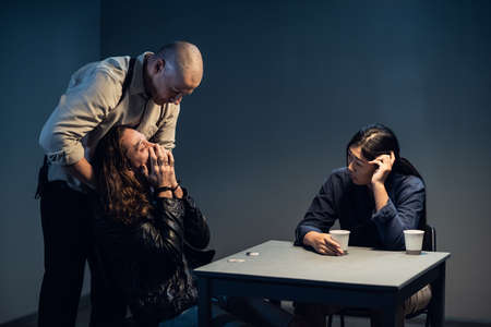 A suspect in a police station laughs madly during an interrogation conducted by investigators.の写真素材