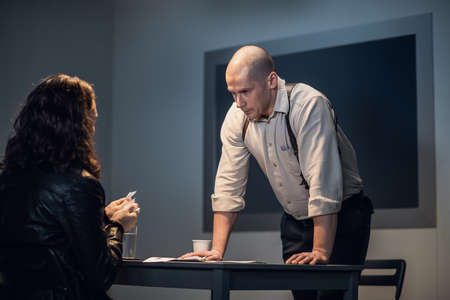 A cheeky guy suspected of a crime tears up documents during an interrogation in front of an investigator.の写真素材