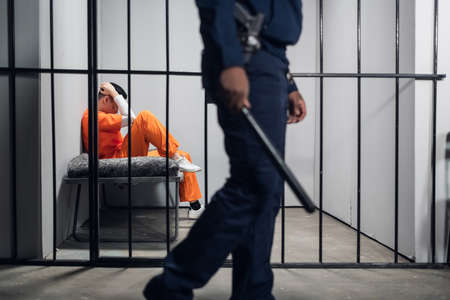 A male warden guards cells with dangerous criminals in a high-security prison. Dangerous professionの写真素材