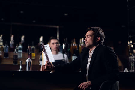 cute man reading the bar menu, sitting at the counter.の写真素材
