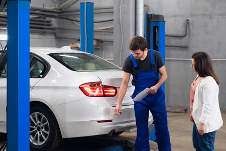 Mechanic in overalls talking with a client about a carの写真素材