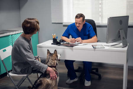 A male doctor talking to a young woman about her dogs diagnosis.の写真素材
