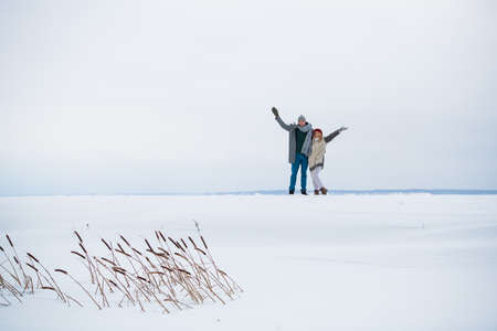 On a white background of a snowy plain, a couple of lovers run and hug during a date.
