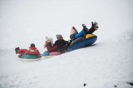 Parents bought their children tubing and now the whole family ride down the ice slide.