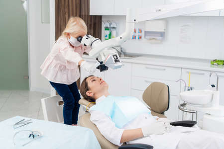 A kid playing with dental equipment during her pediatric dentist visit.の写真素材