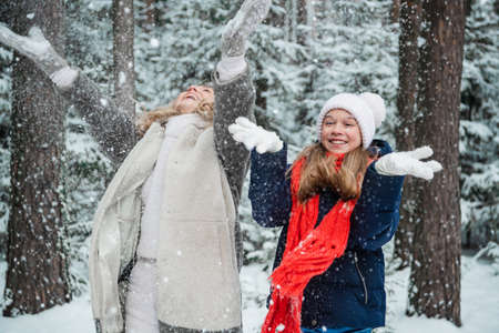 In a family holiday home in the forest, a lovely mother and daughter are resting in winter, enjoying the first snow.の写真素材