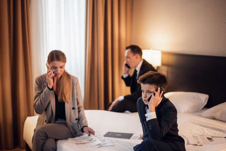 business, technology, internet and hotel concept - business people in the hotel room with their little son.の写真素材