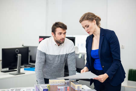 A young office worker getting distracted by his colleagues low neckline, while she is trying to...