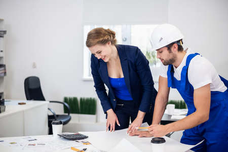 A male and a female construction engineer working on some technical drawings in the office, construction engineering concept.の写真素材