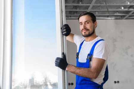 Bearded craftsman checks the plastic window in the apartment