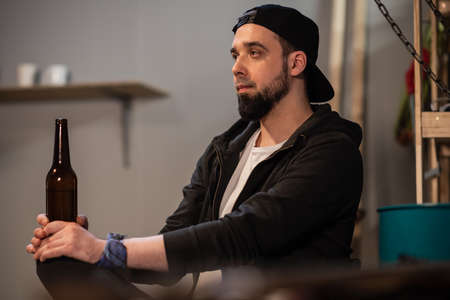 friends guys gathered at a bachelor party in the garage, drinking beer from dark bottles at a partyの写真素材