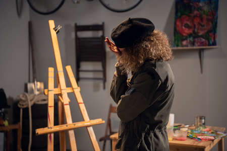 A young female artist is experiencing a creative crisis. Standing in front of an easel in an art...
