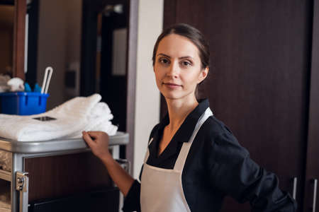 Hotel housekeeper pushing a cleaning supply cart.の写真素材