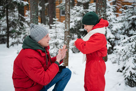 A young caring dad warms his sons hands on a cool winter day in the woods during a walk.
