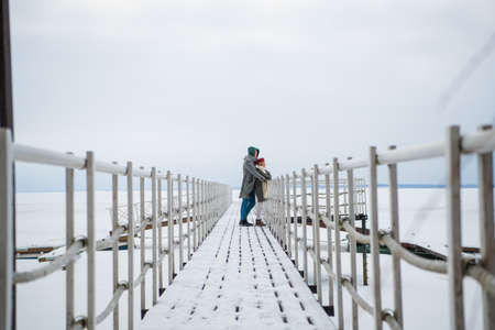 The husband arranged an exit date for his wife in the winter on the river pier in the snow, they enjoy each other.の写真素材