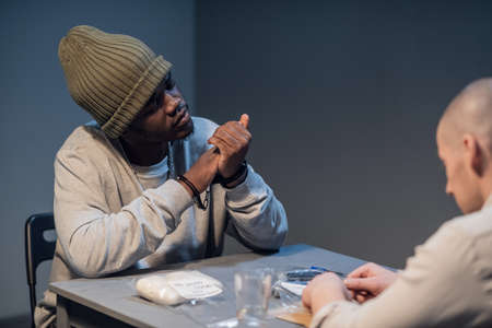 Black accused guy in police station for questioning with a bag of white powder.